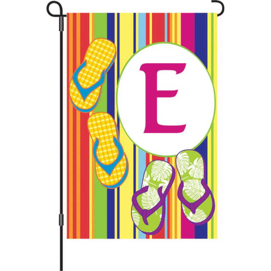 12 in. Summer Monogram Flag - E featuring a vibrant 'E' on a colorful background, displayed outdoors in a garden setting.