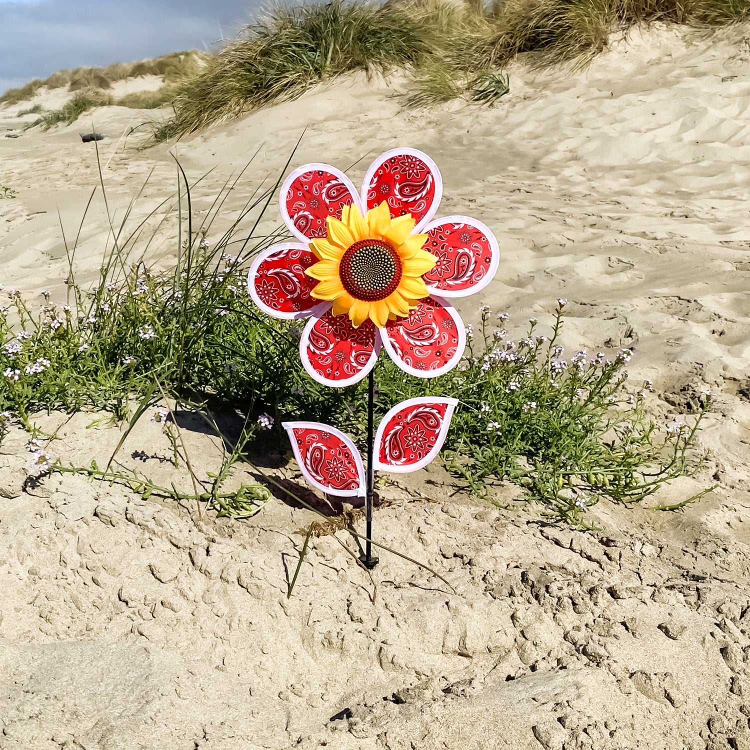 12-inch Paisley Sunflower Spinner with six colorful petals and detailed sunflower center, spinning gently in an outdoor garden setting.