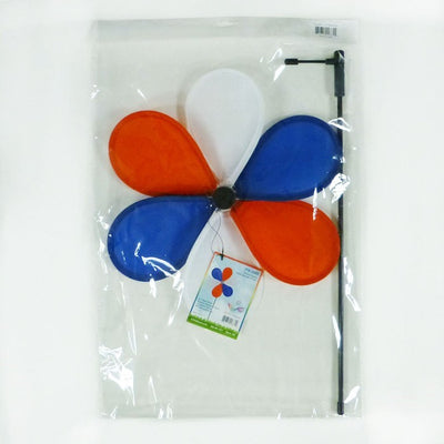 12-inch Patriot Flower spinner with red, white, and blue petals spinning on a 17-inch fiberglass pole in a garden setting.
