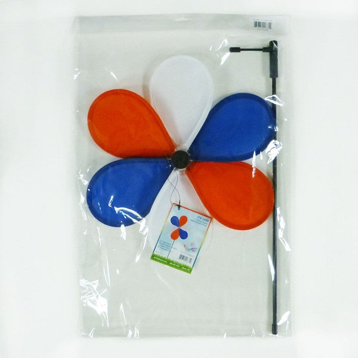 12-inch Patriot Flower spinner with red, white, and blue petals spinning on a 17-inch fiberglass pole in a garden setting.