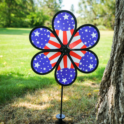 12-inch Patriot Star Flower Spinner with a vivid Stars and Stripes design, spinning on a garden pole in an outdoor setting.