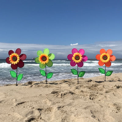 12-inch pink sunflower spinner featuring vibrant petals and realistic center displayed in a garden setting with a fiberglass pole.