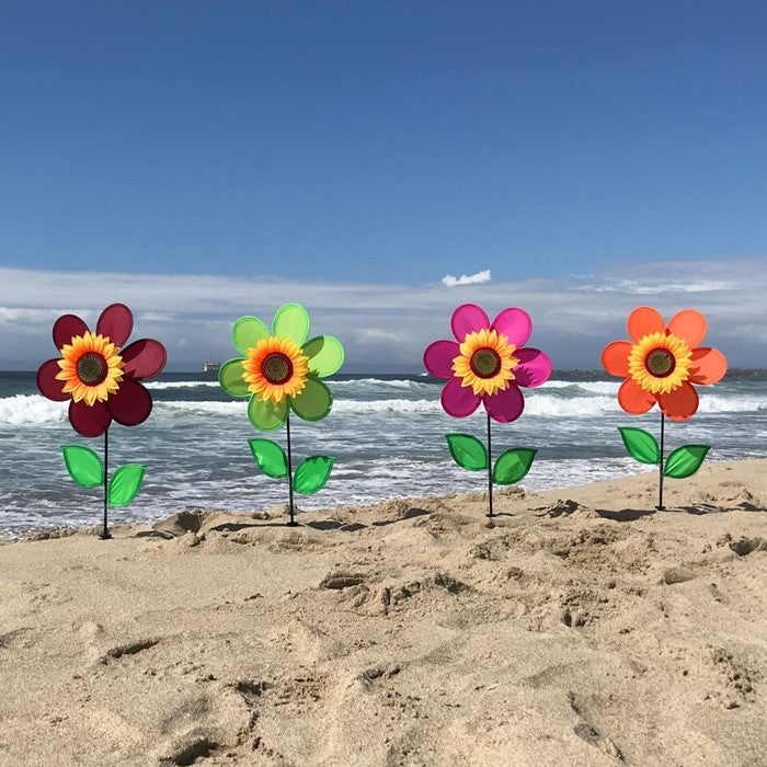 12-inch pink sunflower spinner featuring vibrant petals and realistic center displayed in a garden setting with a fiberglass pole.
