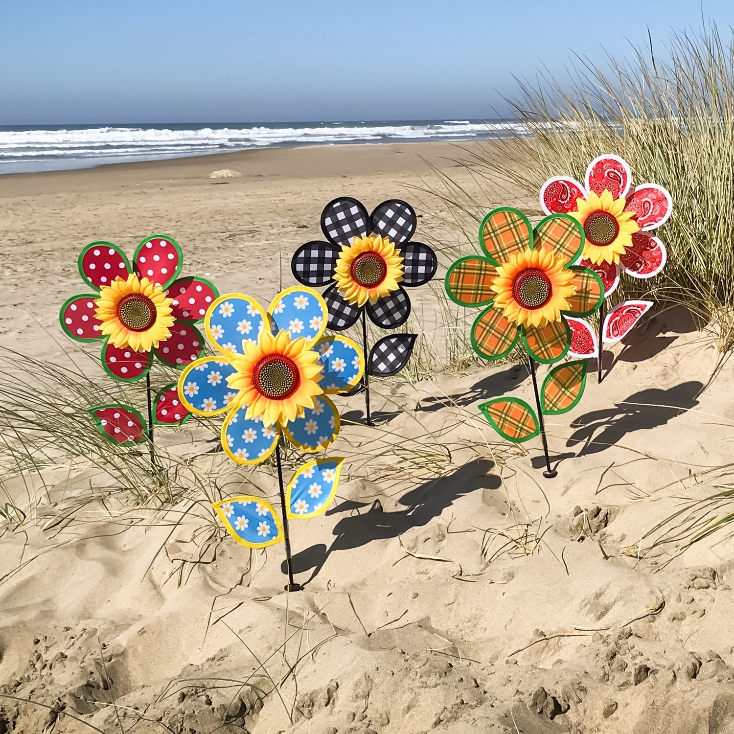 Colorful 12" Polka Dot Sunflower Spinner featuring red and white polka dots, with matching leaves and a sturdy fiberglass pole, displayed outdoors in a garden setting.