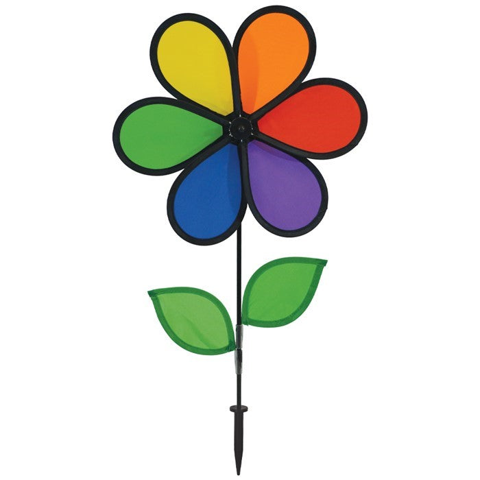 12-inch Rainbow Flower Spinner with six colorful petals and leaves on a fiberglass pole, spinning in the breeze in a garden setting.