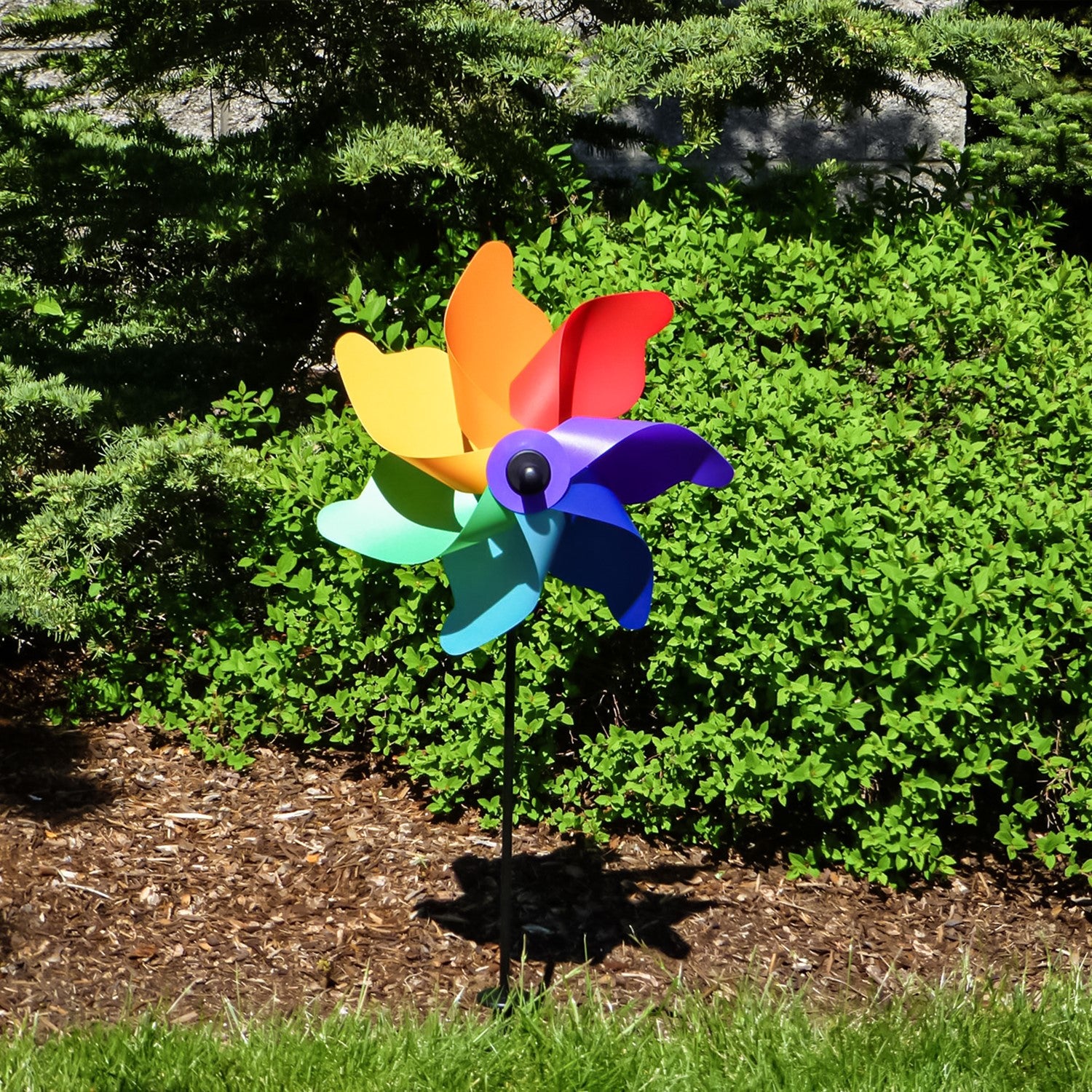 Colorful 12-inch Rainbow Poly Petal Spinner featuring bright petals on a fiberglass pole, spinning pleasantly in a garden setting.