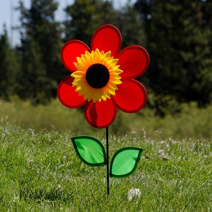 12-inch Red Sunflower Spinner with vibrant red petals and detailed center, spinning on a fiberglass pole in a colorful garden setting.