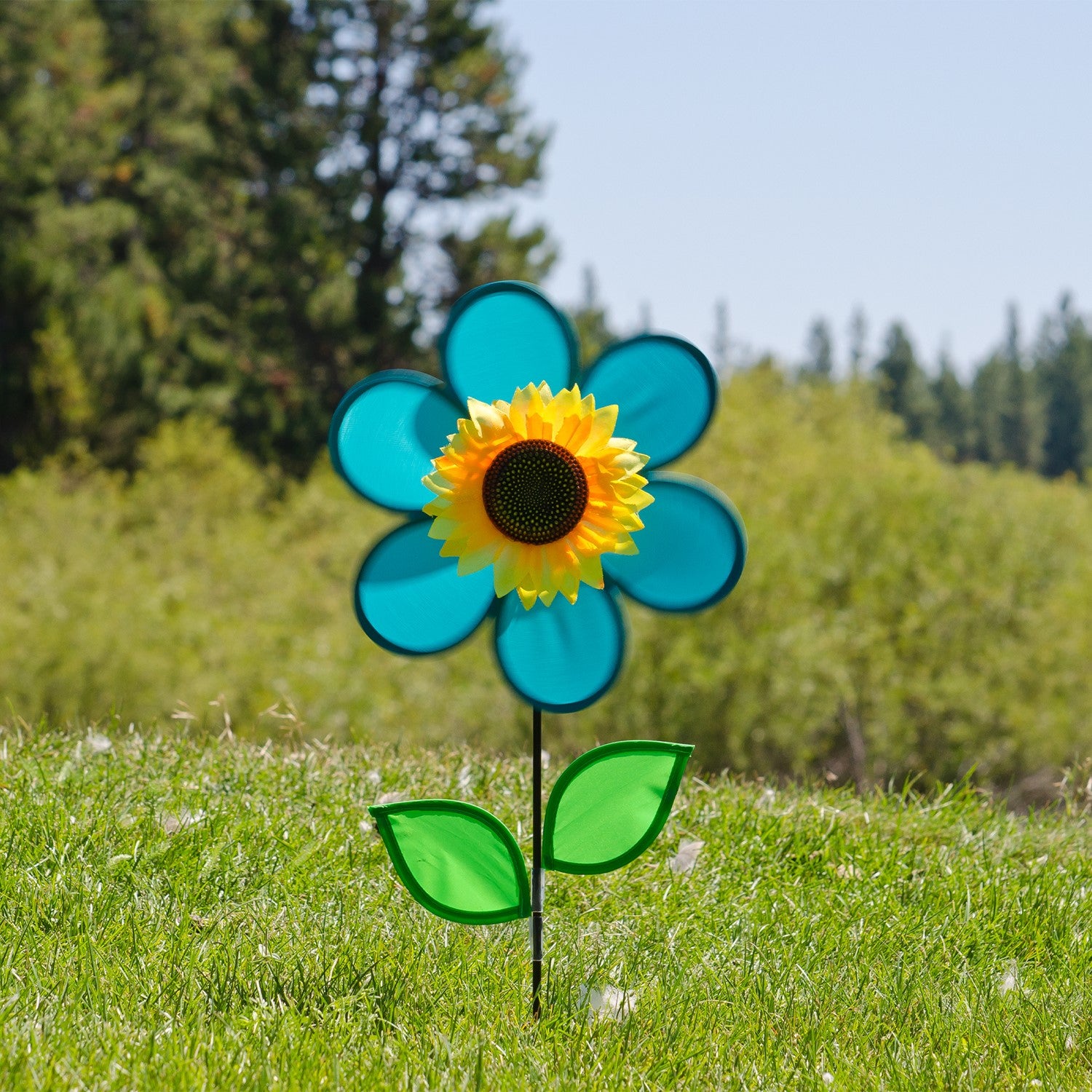 Vibrant 12-inch teal sunflower spinner with bright teal petals, green leaves, and a detailed sunflower center displayed in a garden setting.