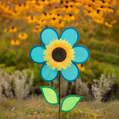 Vibrant 12-inch teal sunflower spinner with bright teal petals, green leaves, and a detailed sunflower center displayed in a garden setting.