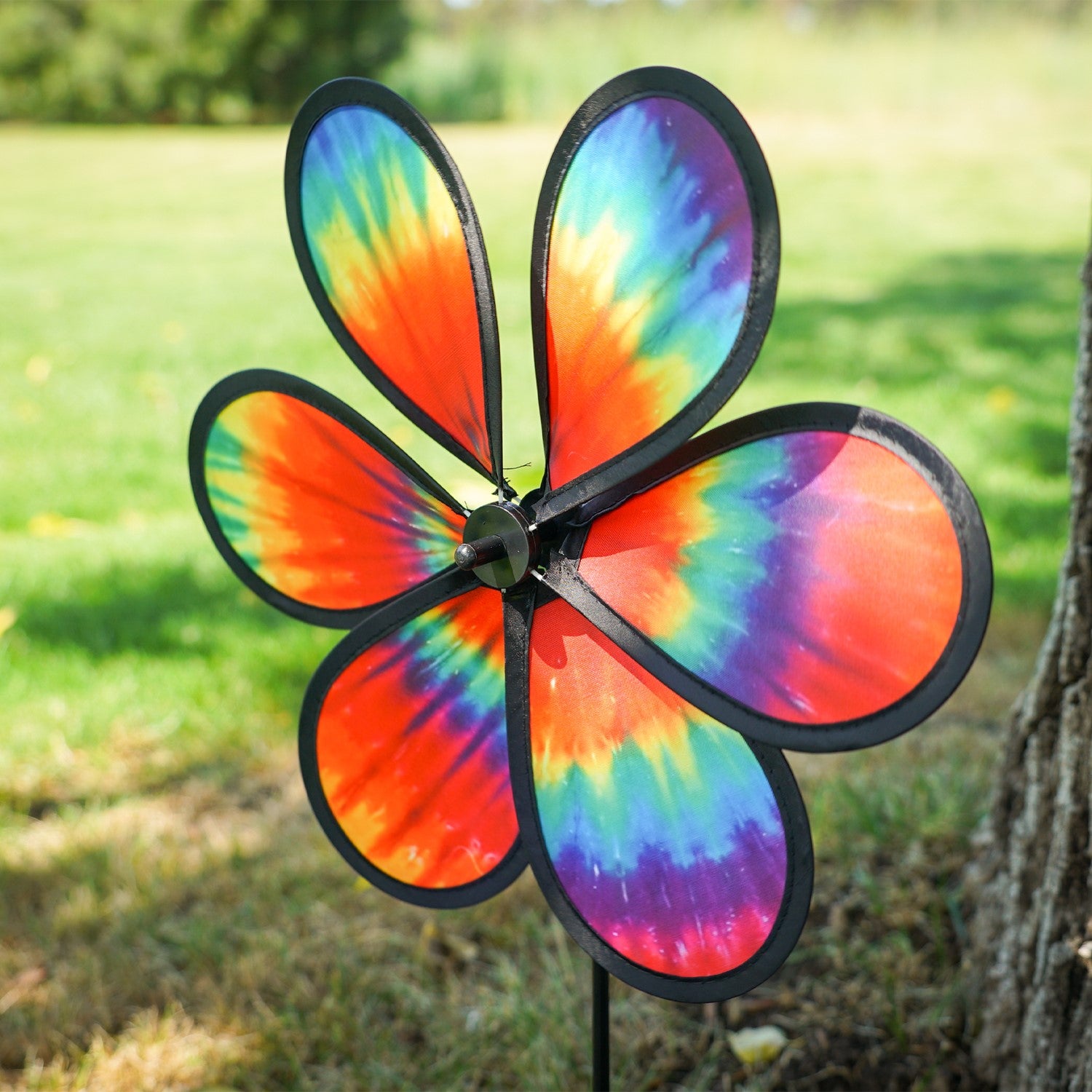 Colorful 12\" Tie Dye Daze Flower Spinner displaying vibrant tie-dye colors, spinning in a sunny garden setting, showcasing its whimsical design.