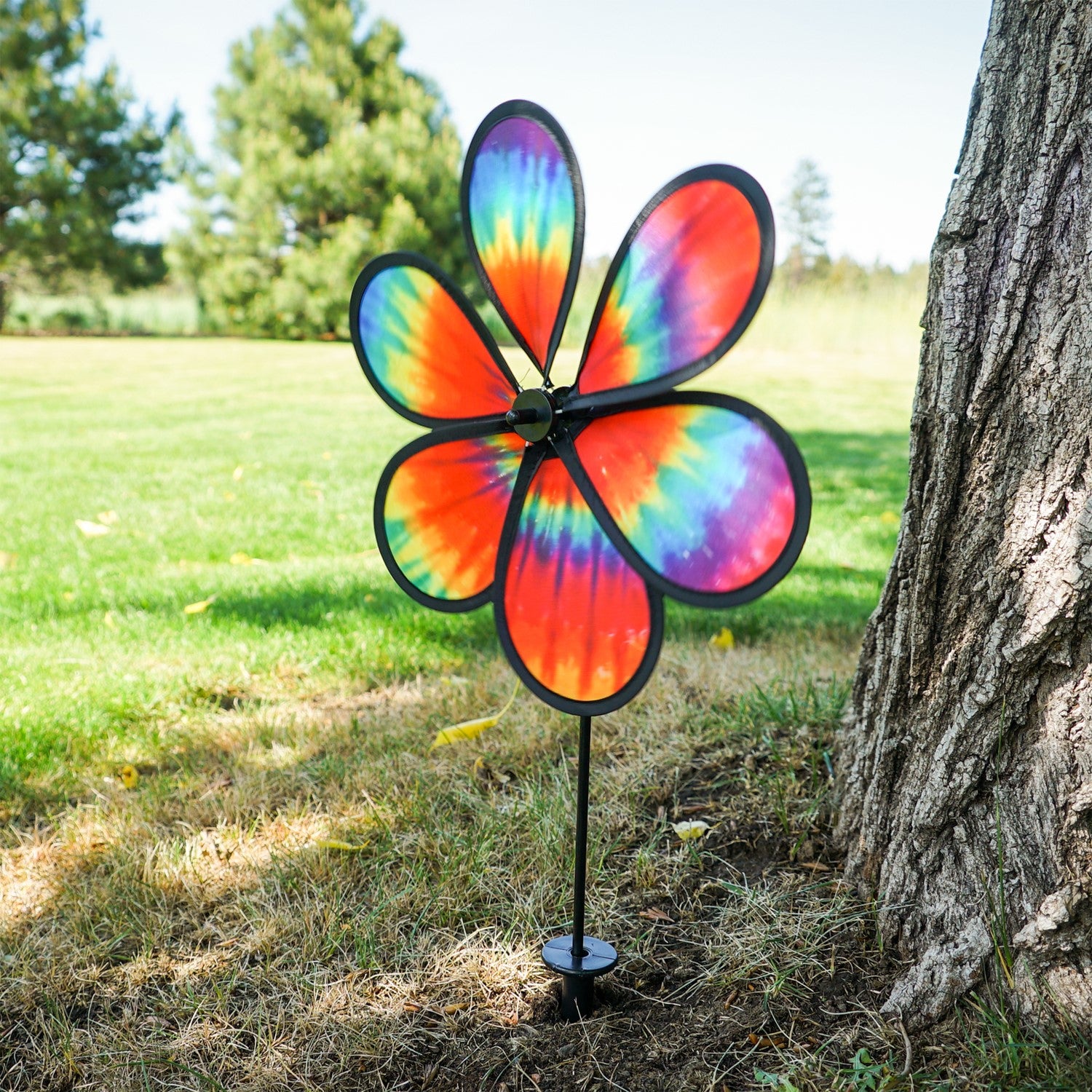 Colorful 12\" Tie Dye Daze Flower Spinner displaying vibrant tie-dye colors, spinning in a sunny garden setting, showcasing its whimsical design.