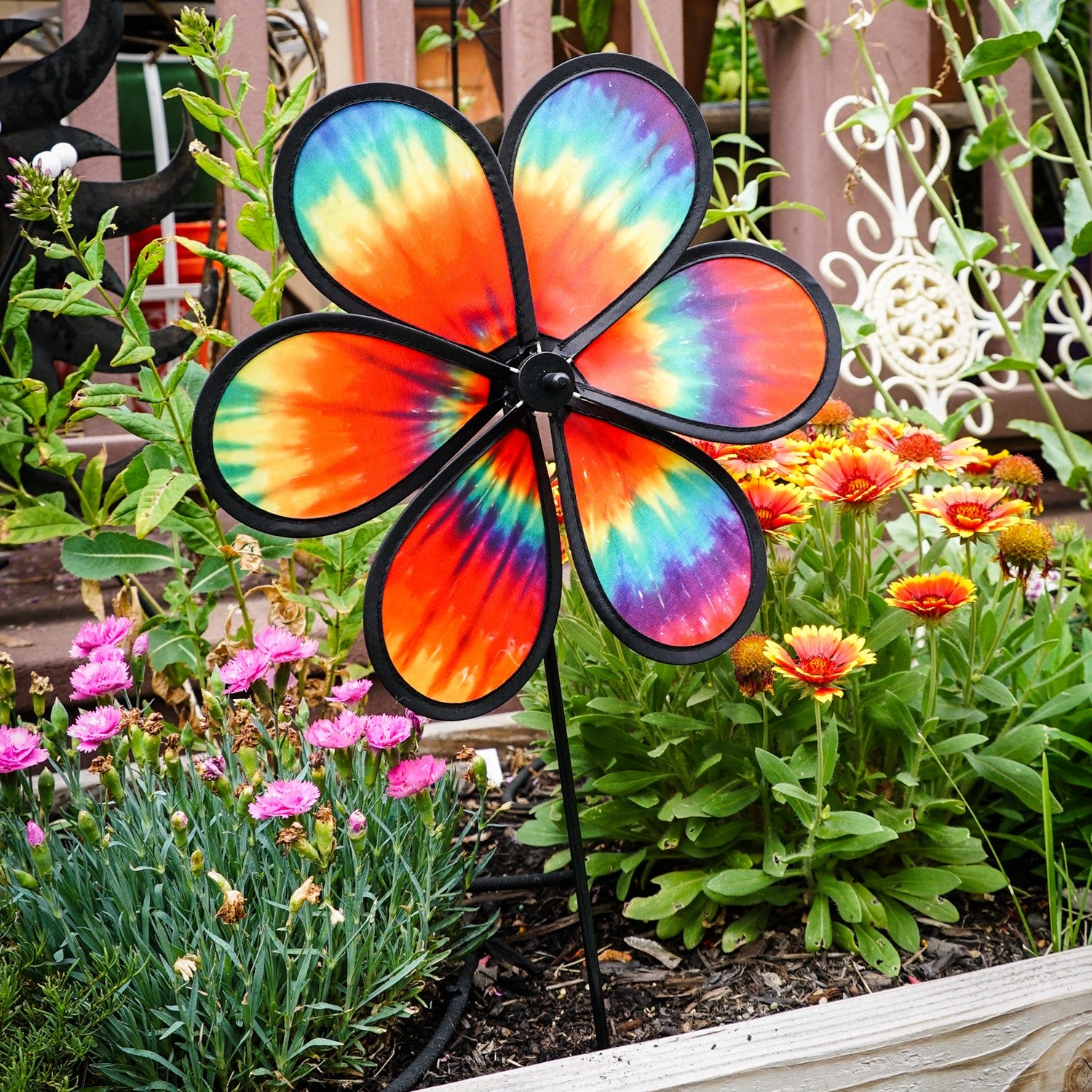 Colorful 12\" Tie Dye Daze Flower Spinner displaying vibrant tie-dye colors, spinning in a sunny garden setting, showcasing its whimsical design.