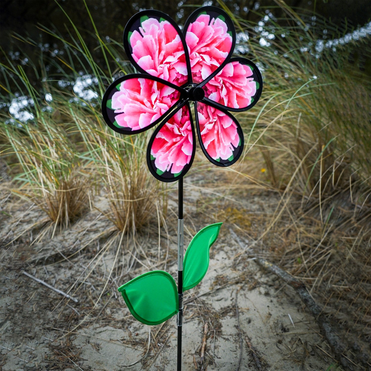 13.5 inch Peony Spinner with realistic printed petals and green leaves spinning in a charming outdoor garden setting.