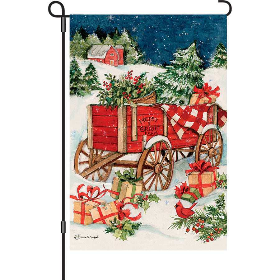 13 in. Elite Oversized Garden Flag featuring a Christmas Wagon design, displayed outdoors on a flag pole amidst a winter setting.