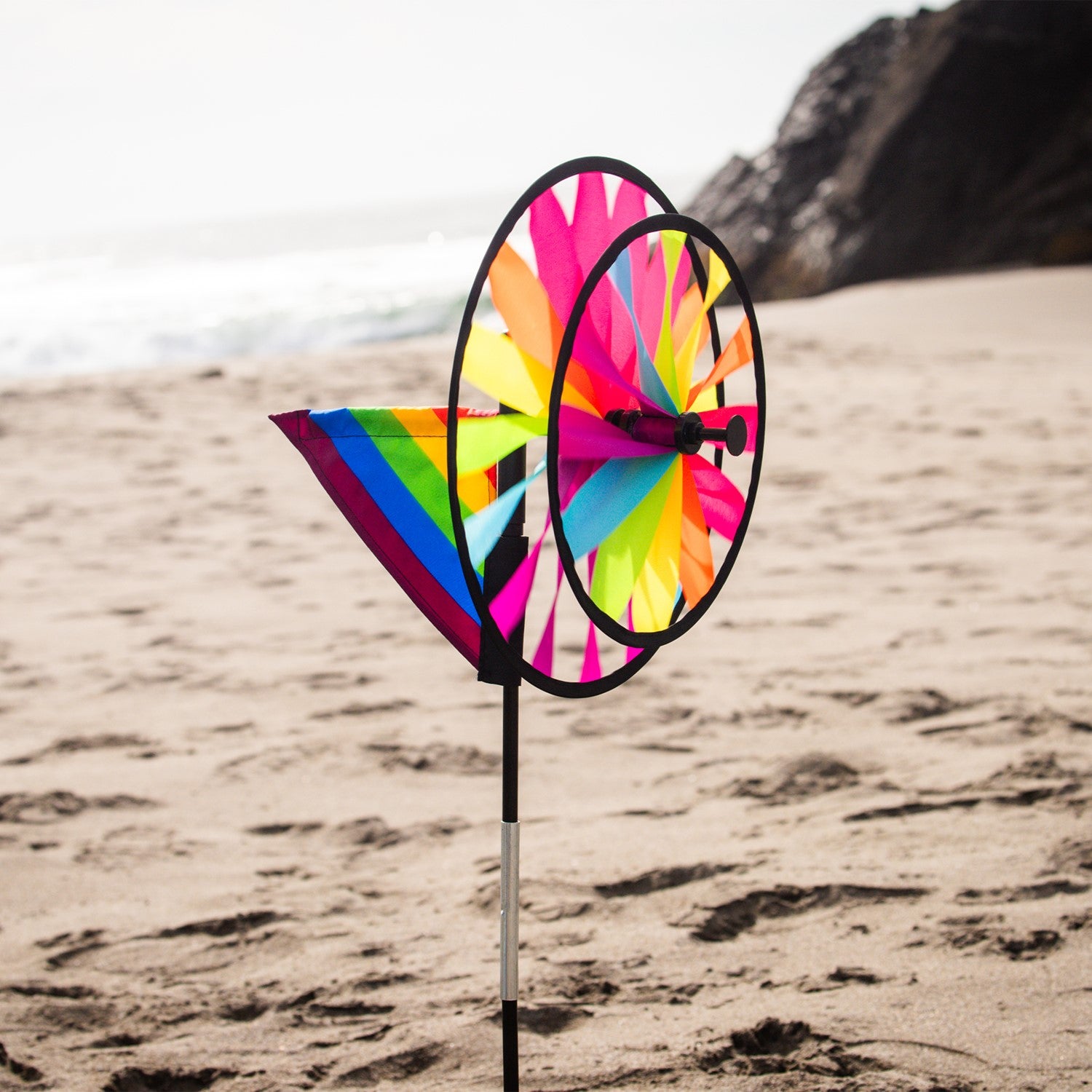 13-inch Fiesta Double Spinner with Wind Sail showcasing vibrant colors and dual spinning wheels, placed in a garden setting.