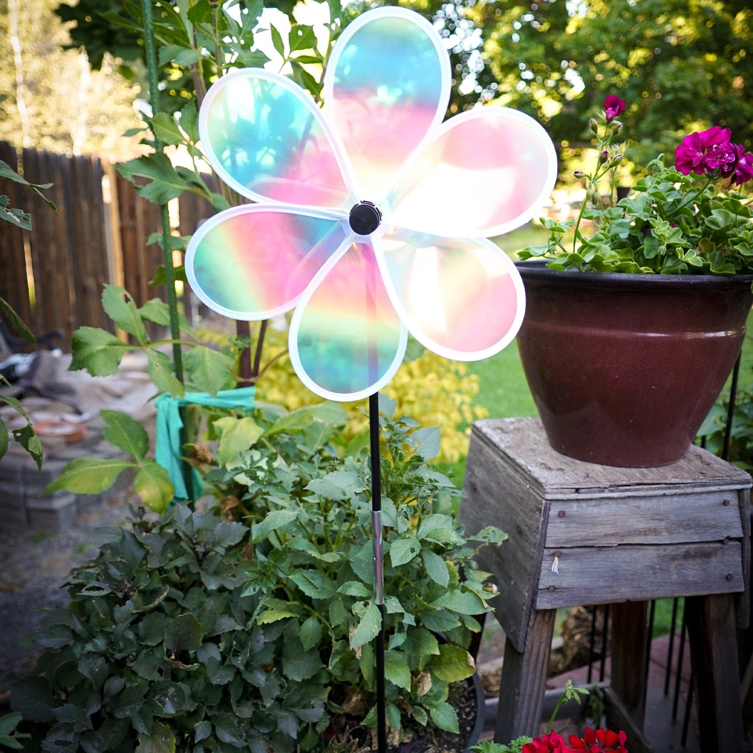 13.5-inch striped iridescent flower spinner with colorful stripes and a shimmering finish, spinning in a garden setting.