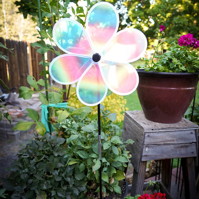 13.5-inch striped iridescent flower spinner with colorful stripes and a shimmering finish, spinning in a garden setting.