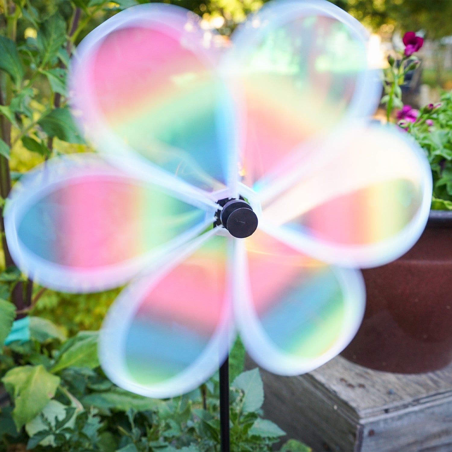 13.5-inch striped iridescent flower spinner with colorful stripes and a shimmering finish, spinning in a garden setting.