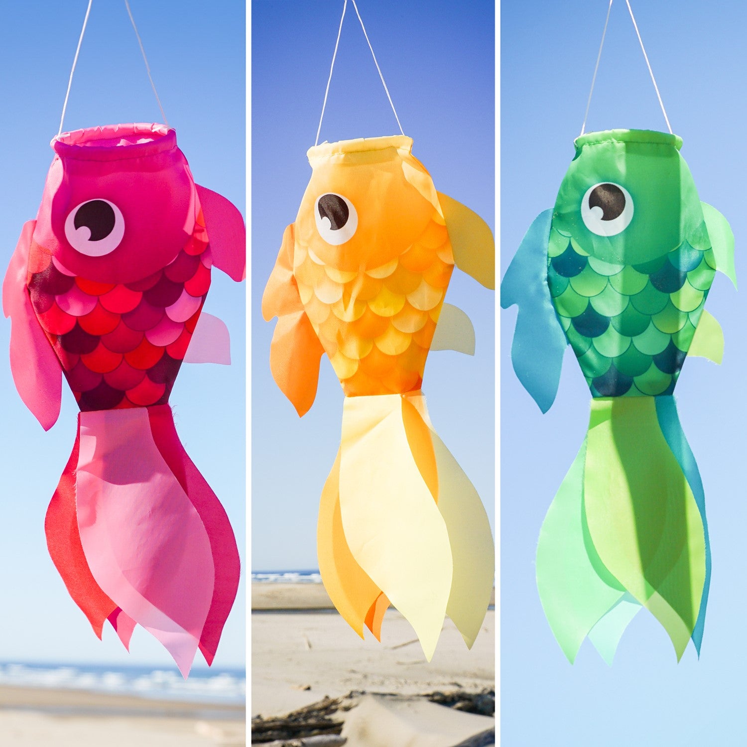 Three colorful Damsel Fish windsocks in pink, yellow, and green, hanging in a garden, gently moving with the breeze under a sunny sky.