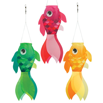 Three colorful Damsel Fish windsocks in pink, yellow, and green, hanging in a garden, gently moving with the breeze under a sunny sky.