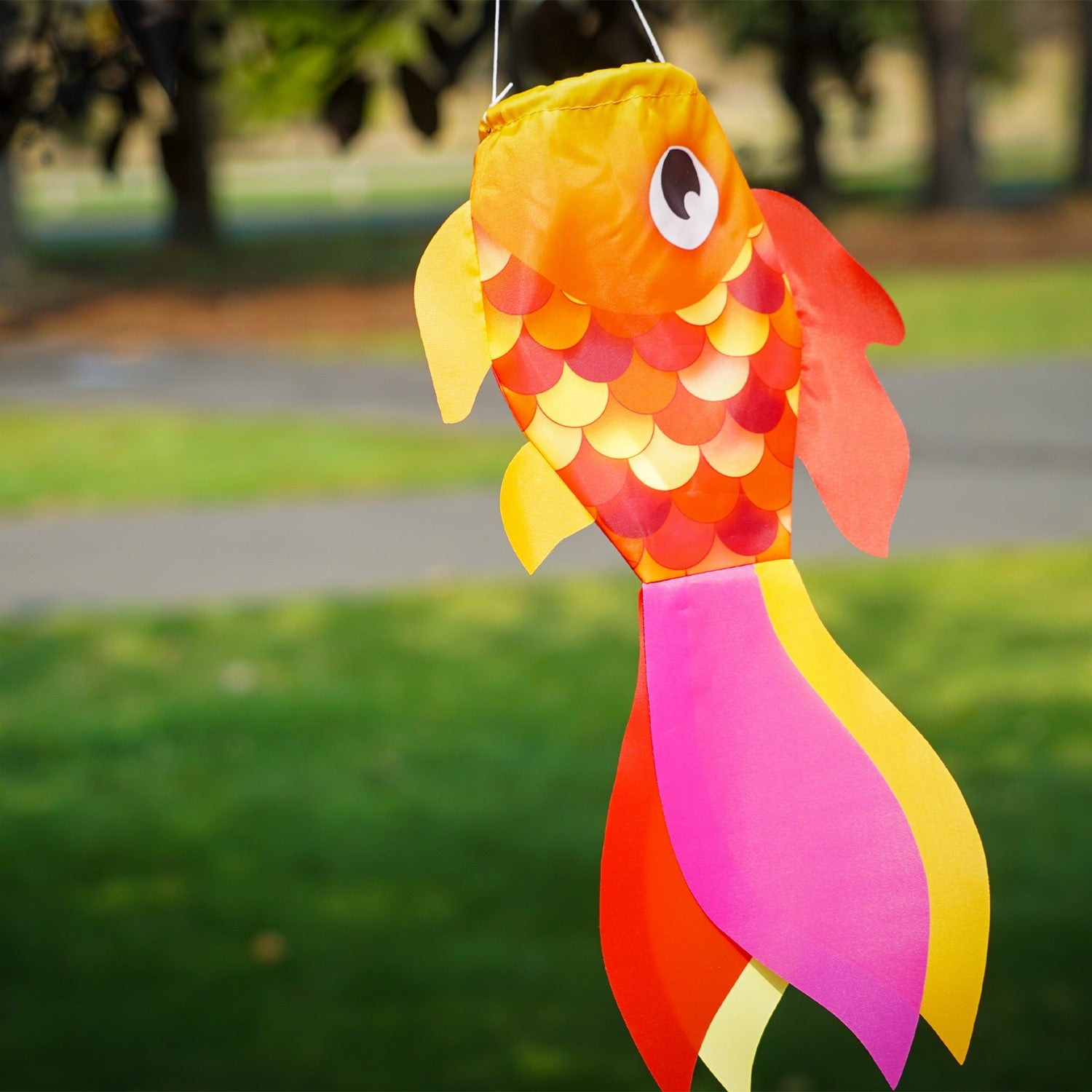 15-inch Hot Damsel Fish windsock in vibrant colors with flapping fins, hung outside in a garden setting to enhance decor.