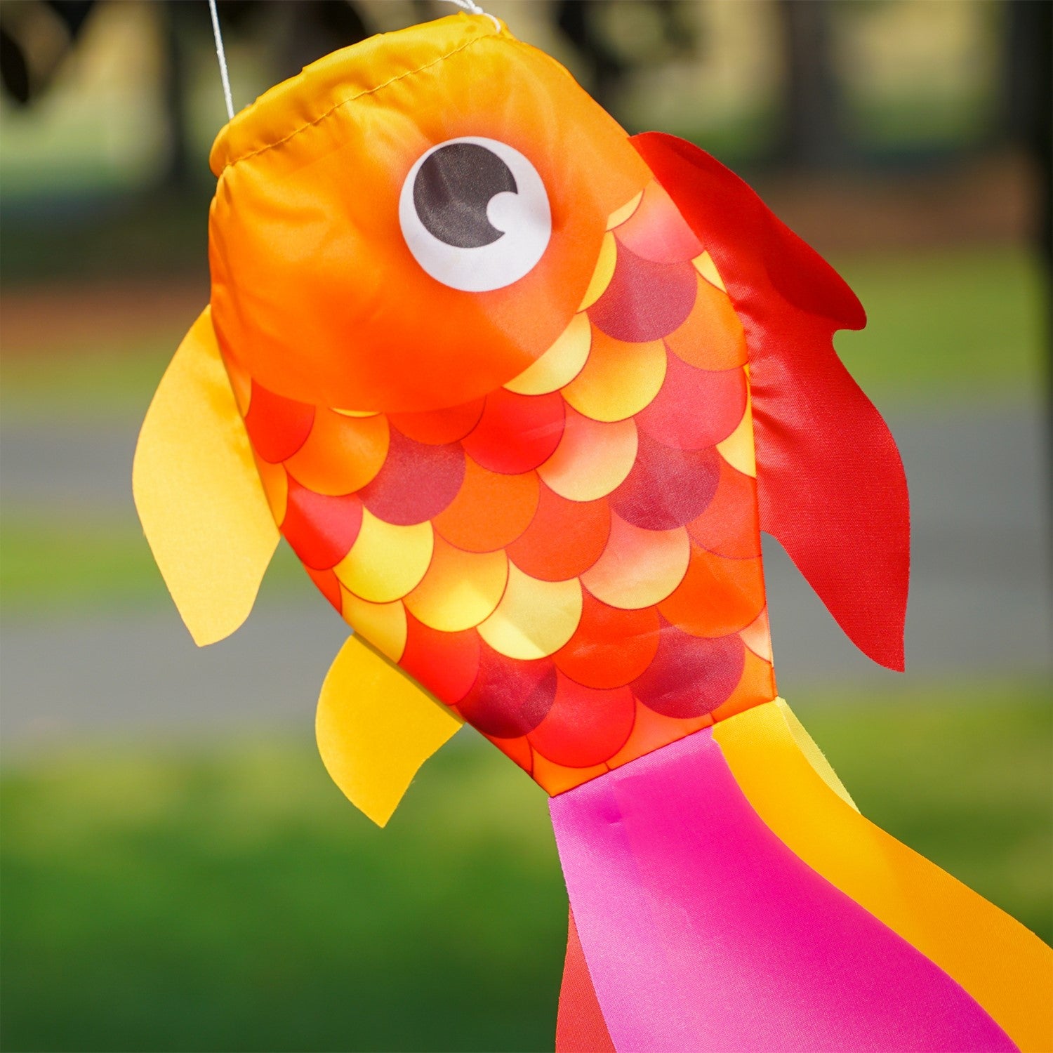 15-inch Hot Damsel Fish windsock in vibrant colors with flapping fins, hung outside in a garden setting to enhance decor.