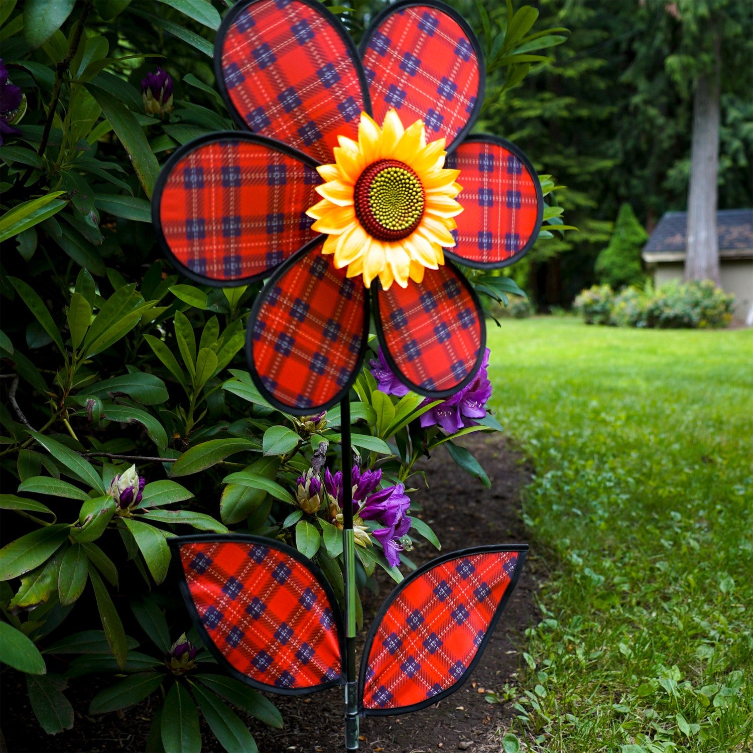 A vibrant 16-inch Red Plaid Flower Spinner with lush green leaves and a sunflower center, rotating gracefully in a garden setting.