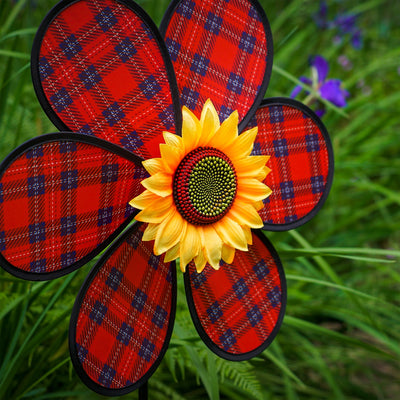 A vibrant 16-inch Red Plaid Flower Spinner with lush green leaves and a sunflower center, rotating gracefully in a garden setting.
