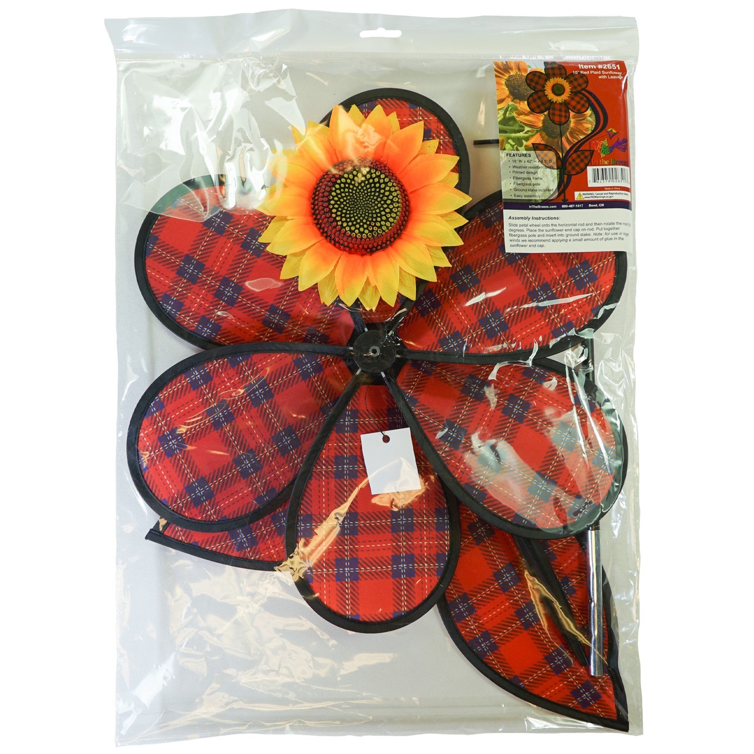 A vibrant 16-inch Red Plaid Flower Spinner with lush green leaves and a sunflower center, rotating gracefully in a garden setting.