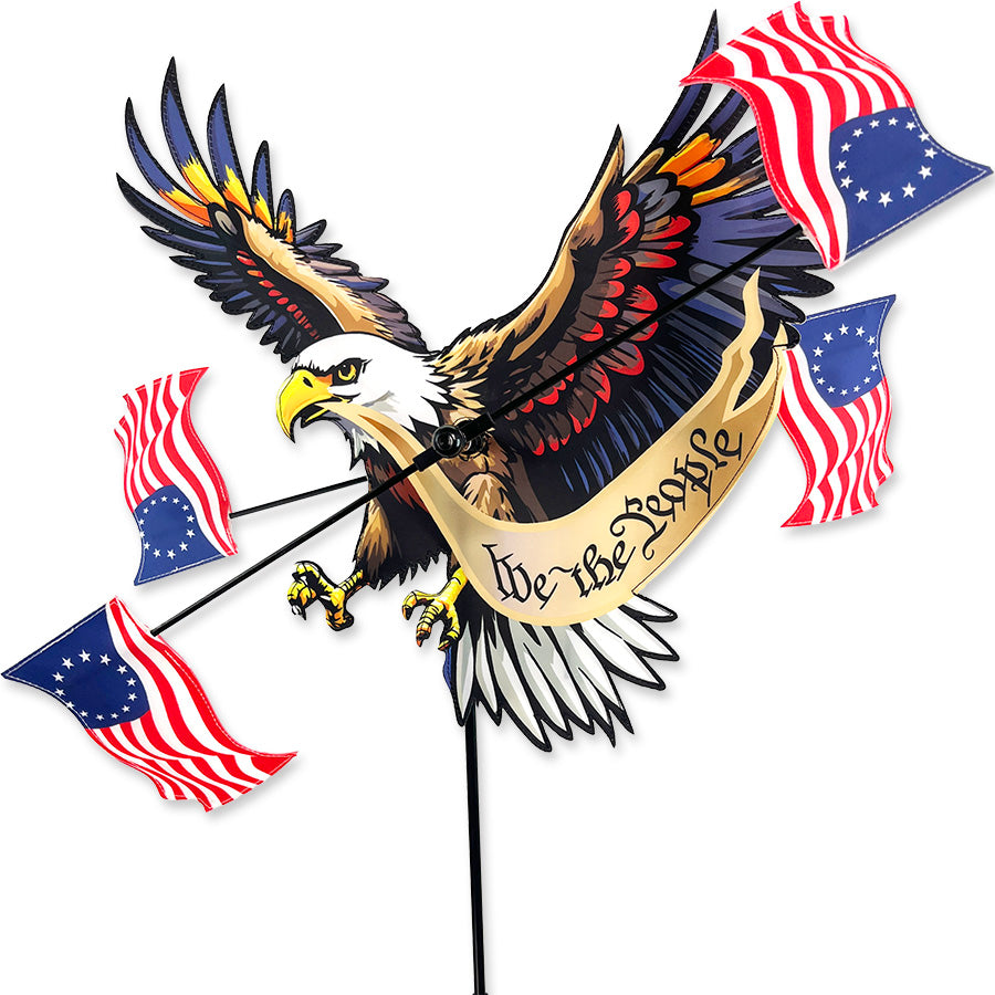 17 in. WhirliGig Spinner with 'We the People' and bald eagle design spinning in a garden setting, celebrating patriotism.