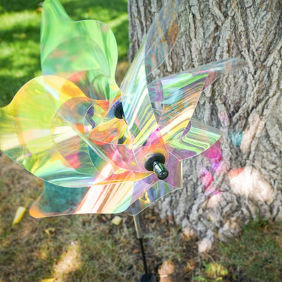 18-inch iridescent pinwheel spinner with colorful Mylar petals spinning on a garden pole, reflecting light in a vibrant outdoor setting.