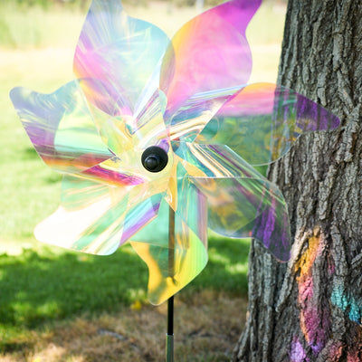 18-inch iridescent pinwheel spinner with colorful Mylar petals spinning on a garden pole, reflecting light in a vibrant outdoor setting.
