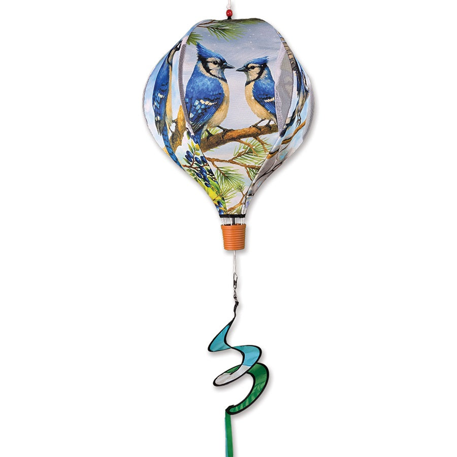 19 in. Pop-Open Hot Air Balloon in Blue Jay design displayed on a garden deck, spinning gracefully in the wind against a clear sky.