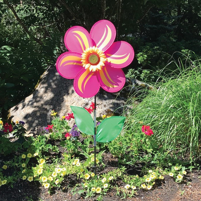 19-inch pink sunflower spinner with six petals, realistic sunflower center, and two green leaves, mounted on a sturdy fiberglass pole in a garden setting.
