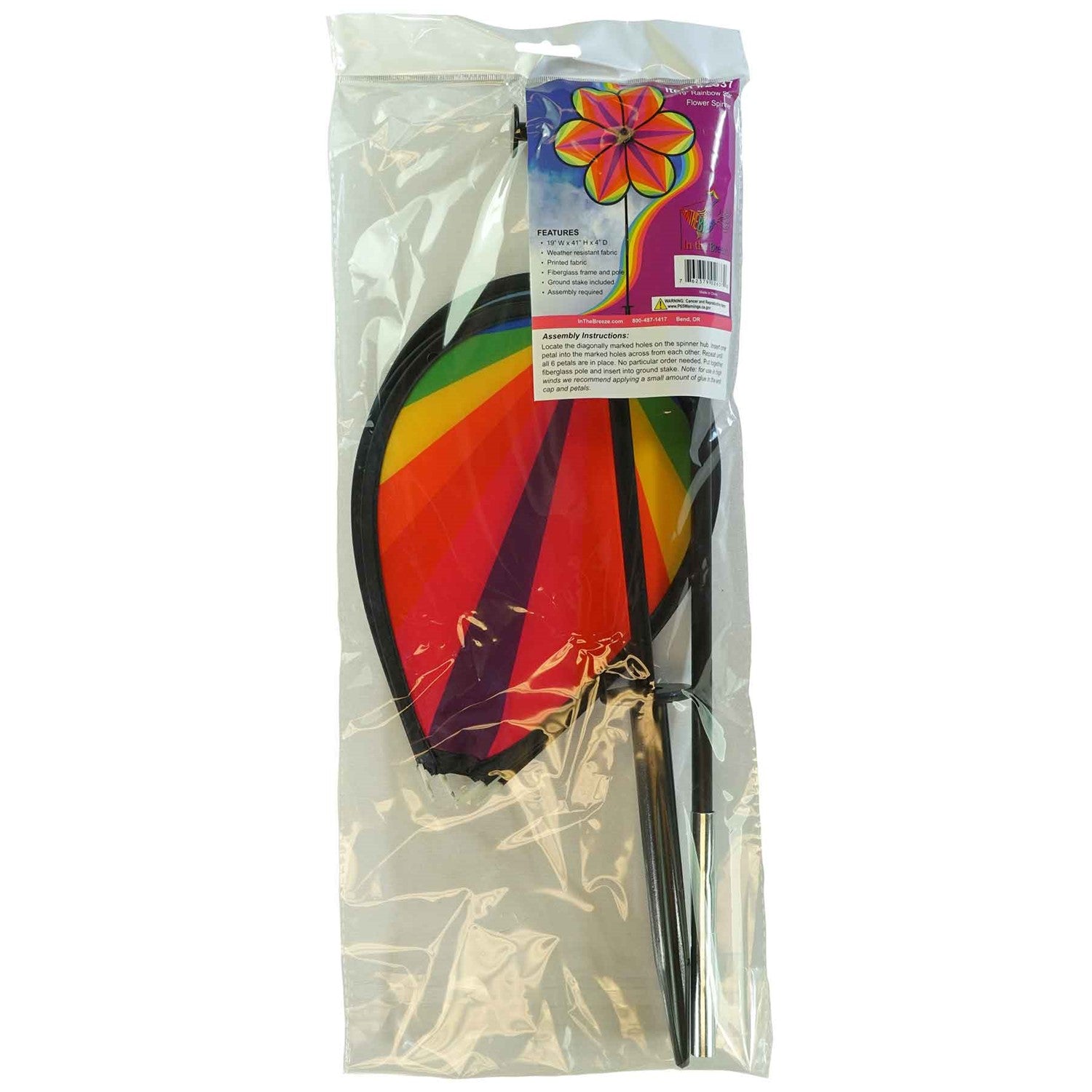 19-inch Rainbow Star Flower Spinner with colorful striped petals spinning in the breeze, displayed in a garden setting.
