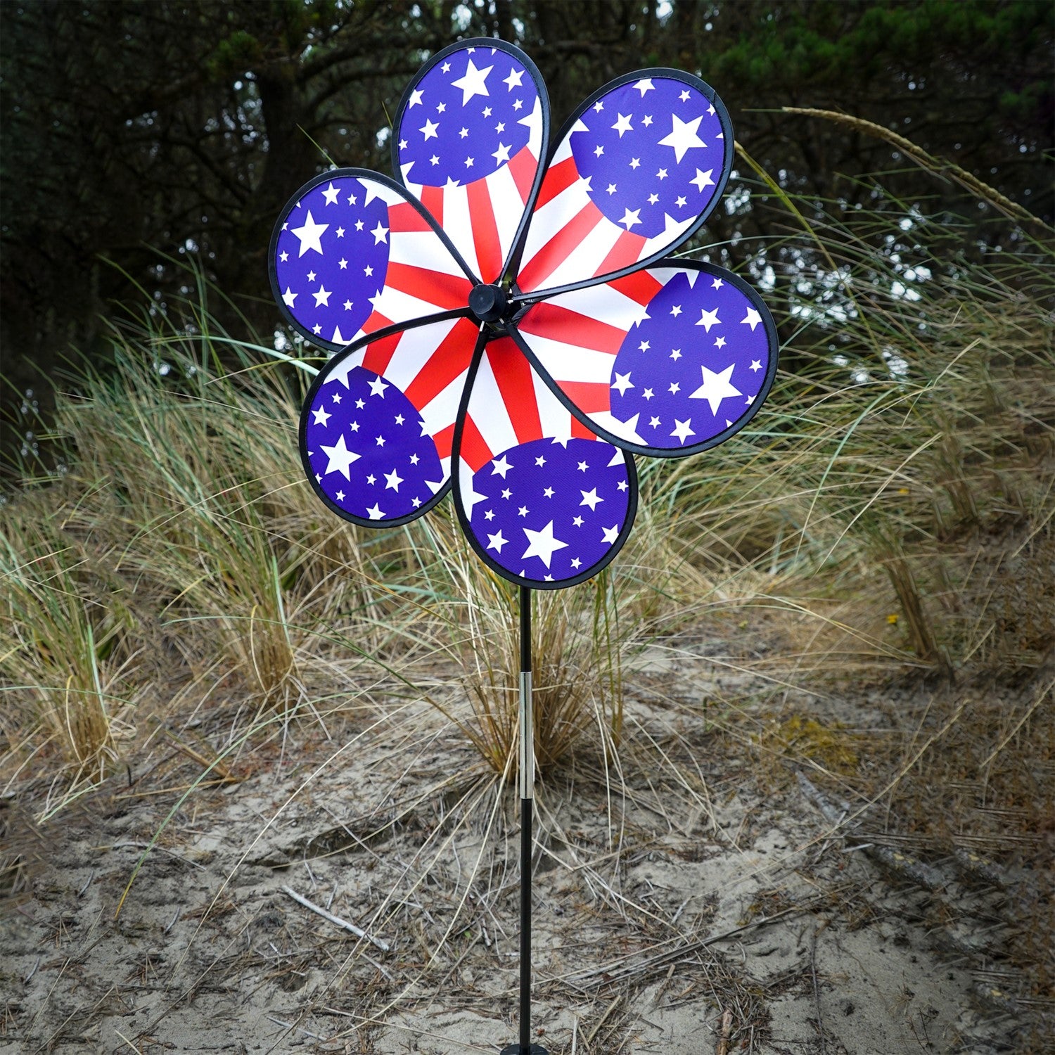 19\" Patriot Star Flower Spinner featuring vibrant stars and stripes design, displayed in a garden setting, spinning gently in the breeze.