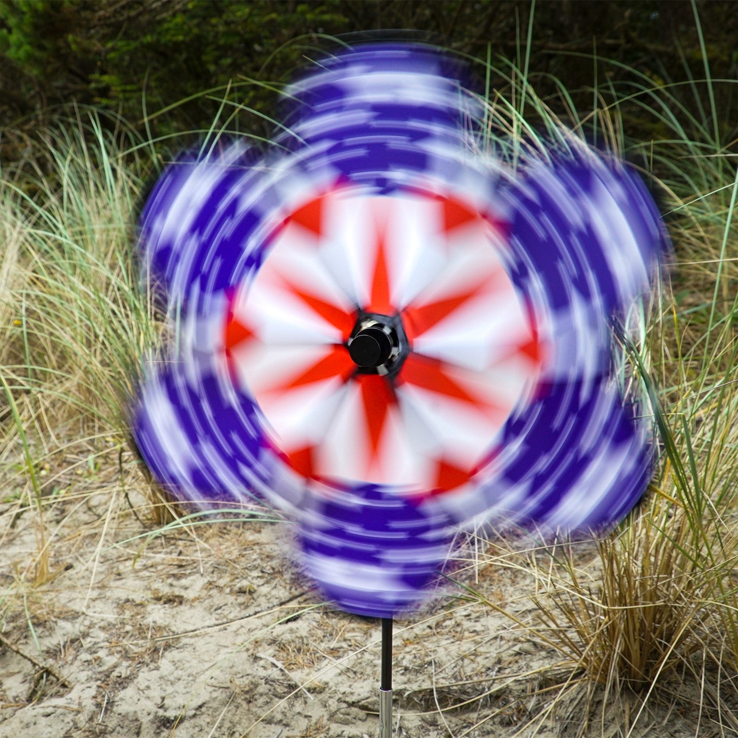 19\" Patriot Star Flower Spinner featuring vibrant stars and stripes design, displayed in a garden setting, spinning gently in the breeze.
