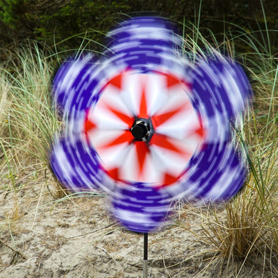 19\" Patriot Star Flower Spinner featuring vibrant stars and stripes design, displayed in a garden setting, spinning gently in the breeze.