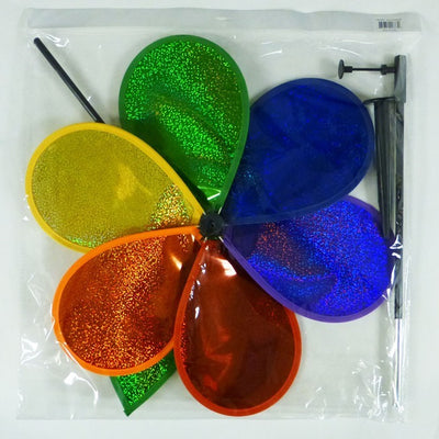 19 inch Rainbow Glitter Flower Spinner with bright Mylar petals spinning on a garden pole in a sunny outdoor yard setting.