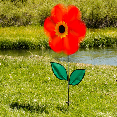 19 inch Red Sunflower Spinner with six bold petals and leaves, rotating on a fiberglass pole in a sunny outdoor garden setting.