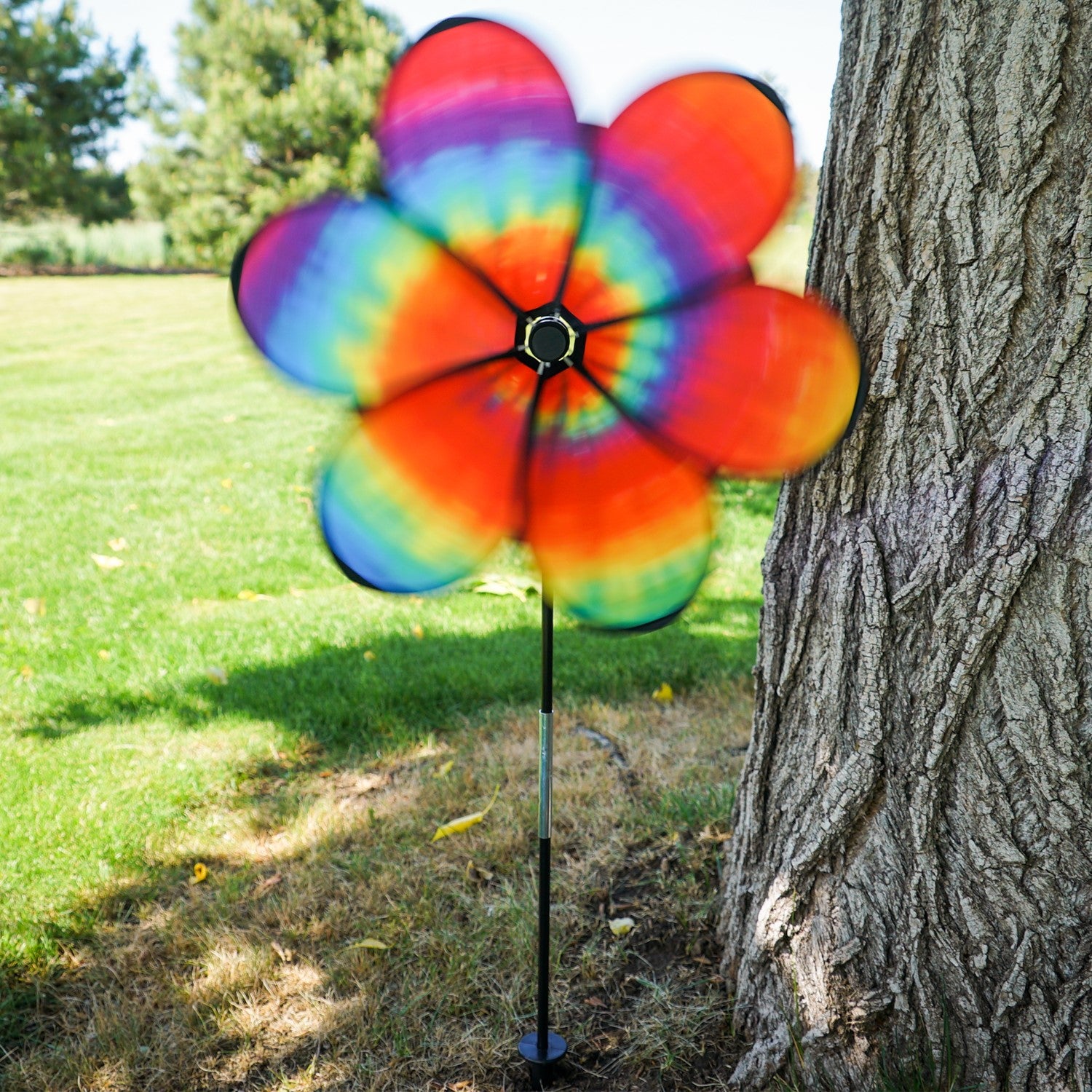 Colorful 19\" Tie Dye Daze Flower Spinner with psychedelic tie-dye design on a garden pole, creating a charming spiral effect in the breeze.