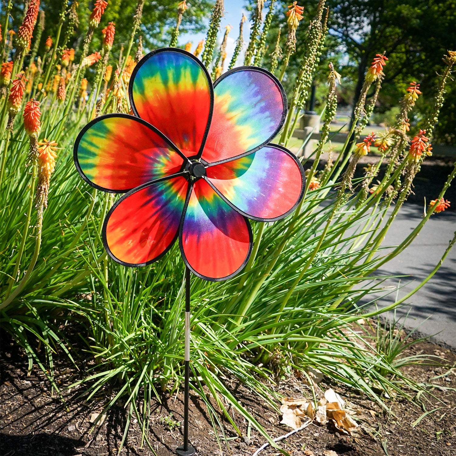Colorful 19\" Tie Dye Daze Flower Spinner with psychedelic tie-dye design on a garden pole, creating a charming spiral effect in the breeze.