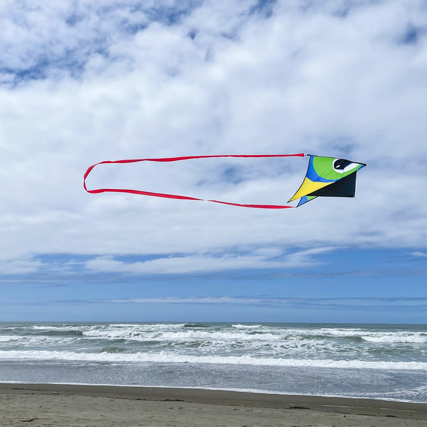 20-foot Continuous Kite Tail in vibrant red attached to a kite, flowing elegantly in the wind against a clear blue sky.