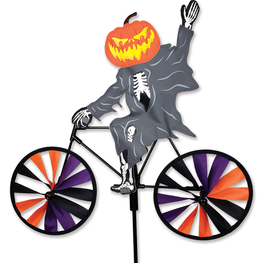 20 in. Bike Spinner - Pumpkin Head Ghost featuring colorful pumpkin head design, spinning in a garden display on a sunny day.