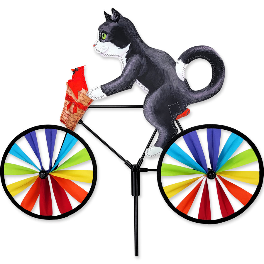 20 inch Tuxedo Cat bike spinner displayed among flowering plants, rotating gracefully in an outdoor setting.