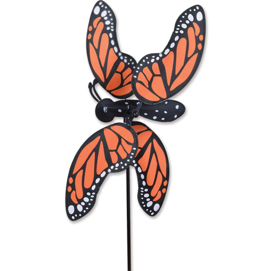 A 20 in. Monarch Butterfly Spinner showcasing vibrant colors, spinning gracefully in an outdoor garden setting with blooming flowers.