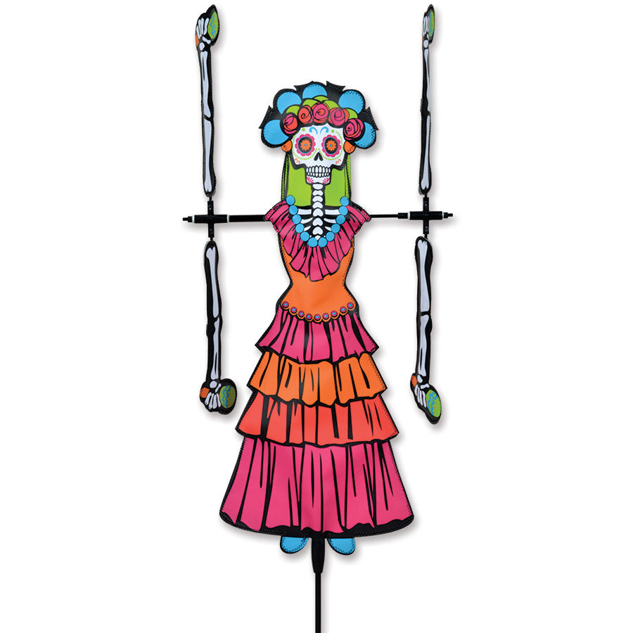20 in. Day of the Dead Woman WhirliGig Spinner showing vibrant colors and details in a garden setting, spinning in a light breeze.