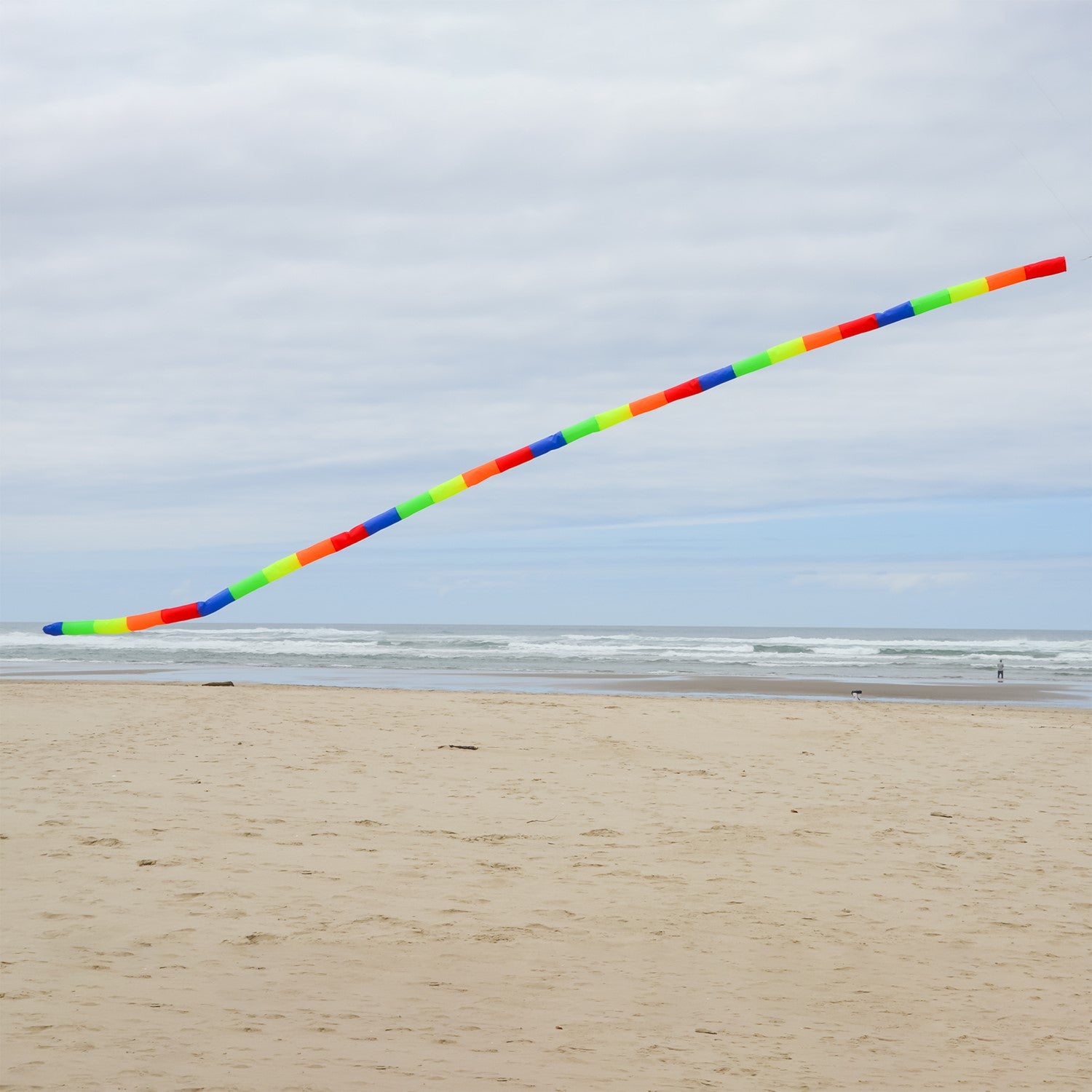 20' Rainbow Tube Tail featuring vivid rainbow stripes designed to enhance kite displays, showcased in an outdoor setting with a clear sky.