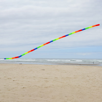 20' Rainbow Tube Tail featuring vivid rainbow stripes designed to enhance kite displays, showcased in an outdoor setting with a clear sky.