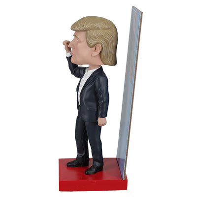 2025 Inauguration Limited Edition Donald Trump Bobblehead featuring a raised fist and American flag backdrop displayed on a shelf.